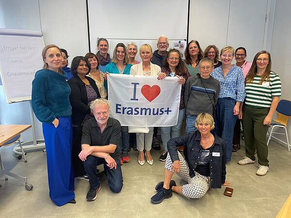 Kursleitende und Mitarbeitende der vhs Olching halten ein Banner mit der Aufschrift I love Erasmus+